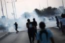 Bahraini protesters run for cover from tear gas fired by riot police during clashes following a demonstration against the arrest of the head of the Shiite opposition movement Al-Wefaq and former MP Sheikh Hassan Isa, on August 28, 2015, in Sitra