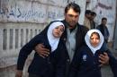An Afghan man assists two schoolgirls in the vicinity of an attack close to the Pakistan consulate in Jalalabad, on January 13, 2016