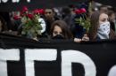 Masked protesters carry a banner and roses while marching in Sao Paulo, Brazil, Thursday, June 19, 2014. The protest in Sao Paulo, Brazil's biggest city that is hosting a World Cup match, was called by the Free Fare movement, the group that was behind the first protests last year that sparked roiling anti-government demonstrations across Brazil. (AP Photo/Eduardo Verdugo)
