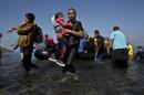 A Syrian refugee man carrying his daughter rushes to the beach as he arrives on a dinghy from the Turkish coast to the northeastern Greek island of Lesbos, Sunday, Oct. 4 , 2015. The U.N. refugee agency is reporting a 