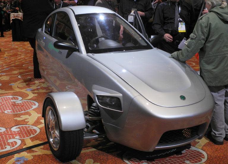 Members of the media inspect a prototype of three-wheeled car, the brainchild of Paul Elio, founder and CEO of Elio Motors, on the sidelines of the 2014 Consumer Electronics Show (CES) January 9, 2014 in Las Vegas