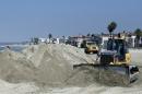 A bulldozer works to pile sand on a temporary berm to protect beach front homes on, Friday, Sept. 5, 2014, in Long Beach, Calif. Southern California is in for another round of high surf generated by what is currently Hurricane Norbert in the Pacific Ocean off Baja California. (AP Photo/Chris Carlson)