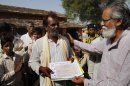 In this Friday, May 25, 2012, photo Prof. Anil Gupta, right, gives a certificate to Ghanshyam Lal, an innovator, during his visit for the Shodh Yatra (Journey for the Search of Knowledge) in the village of Dabati in the Sehore district of Madhya Pradesh, India. Gupta and his aides have uncovered more than 25,000 inventions. Many of the cheap, simple ideas he spreads for free from one poor village to another with the inventor's blessing. Some he is working to bring to market, ensuring the innovator gets the credit and the profit that will spur others to create as well. Many ideas are simply documented in his database waiting for some investor to spot their potential. (AP Photo/Rafiq Maqbool)