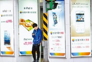 專利訴訟打不完！美國際貿易委員會４日裁定蘋果侵犯三星專利。圖為民眾在台北市三星手機與蘋果平板電腦廣告看板前駐足。（本報資料照片/陳信翰攝）