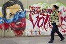 A woman walks past a mural depicting Venezuelan President Hugo Chavez in Caracas