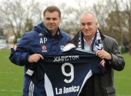 Melbourne Victory coach Ange Postecoglou (L) presents Liverpool football legend Craig Johnston a Victory playing shirt after a team training session in Melbourne on July 23, 2013