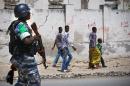 Somali youths look on as they walk past a Ugandan police officer serving as part of a Formed Police Unit (FPU) with the African Union Mission in Somalia (AMISOM) walks past during a foot patrol in Mogadishu on November 9, 2012