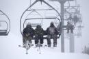 Handout of of skiers riding up a chair lift as snow falls on Mammouth Mountain in California