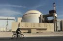 FILE - In this Oct. 26, 2010 file photo, a worker rides a bicycle in front of the reactor building of the Bushehr nuclear power plant, just outside the southern city of Bushehr. Iran and six world powers have agreed on how to implement a nuclear deal struck in November, with its terms starting from Jan. 20, officials announced Sunday. (AP Photo/Mehr News Agency, Majid Asgaripour, File)