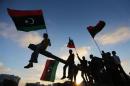 Boys carrying flags sit on a tank in Benghazi during the third anniversary of an attack by pro-Gaddafi forces on Benghazi