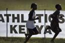 In this photo taken Sunday, Jan. 31, 2016, junior athletes run past a sign for Athletics Kenya at the Discovery cross country races in Eldoret, western Kenya. Two Kenyan athletes Joy Sakari and Francisca Koki Manunga who are both serving a four-year ban for doping at the 2015 world championships say the country's governing body for track and field chief executive of Athletics Kenya, Isaac Mwangi, asked them each for a US dlrs 24,000 bribe to reduce their suspensions. (AP Photo/Ben Curtis)