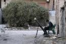A Free Syrian Army fighter listens to music as he sits beside a rocket launcher in Damascus