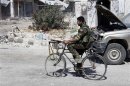 A soldier loyal to the Syrian regime rides a bicycle in Qusair