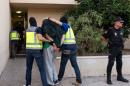 Spanish police officers lead a detained man into a police station during an operation in Melilla, southern Spain