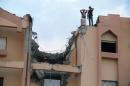 Two men stand on the roof of a damaged building after a Libyan war plane crashed in Tobruk