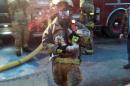This photo provided by Gordon Cole, firefighter Scott Hemmelsbach holds a python after rescuing it from a burning home in Muskegon, Mich., on Sunday, March 30, 2014. Hemmelsbach said that he reluctantly agreed to enter the two-story, smoke-filled house Sunday night to retrieve the snake. He says he cradled the "weighty" snake before carrying it to safety.(AP Photo/Courtesy of Gordon Cole)