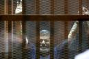 Former Egyptian President Mursi waves during his trial at a court in the outskirts of Cairo