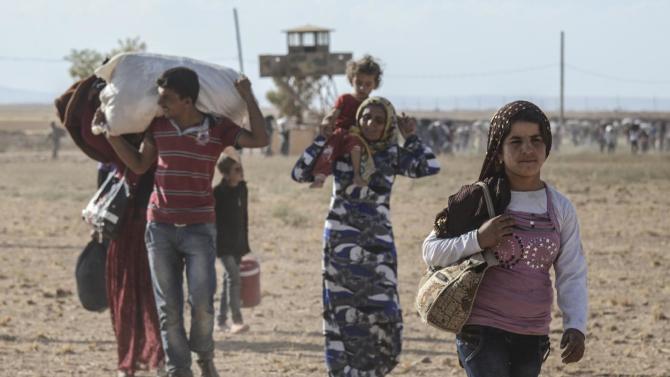 Syrian Kurds cross the border between Syria and Turkey in Sanliurfa province, on September 19, 2014