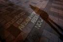 A man casts a shadow near a message written in chalk during a vigil for Abdirahman Abdi in Ottawa