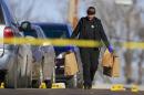 A crime lab investigator carries bags of evidence past markers on the road at the scene of a shooting in Omaha, Neb., Saturday, Jan. 24, 2015. Two women were shot to death and six people were wounded early Saturday at a house party in Omaha. (AP Photo/Nati Harnik)