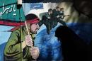 A woman walks past murals of Iranian soldiers marching during the Iran-Iraq war (1980-88), on Palestine square in Tehran