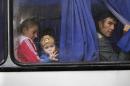 People look through a bus window as they depart as refugees to Russia in the city of Donetsk, eastern Ukraine Monday, July 14, 2014. Five busloads of Internally Displaced People from the towns of Slavyansk, Karlovka, Maryinka and Donetsk left here Monday morning for the Rostov region in Russia to ask for refugee status there. (AP Photo/Dmitry Lovetsky)