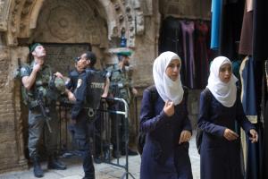 Palestinian women walk past an Israeli police checkpoint &hellip;
