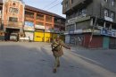 An Indian policeman patrols a deserted road during restriction in Srinagar