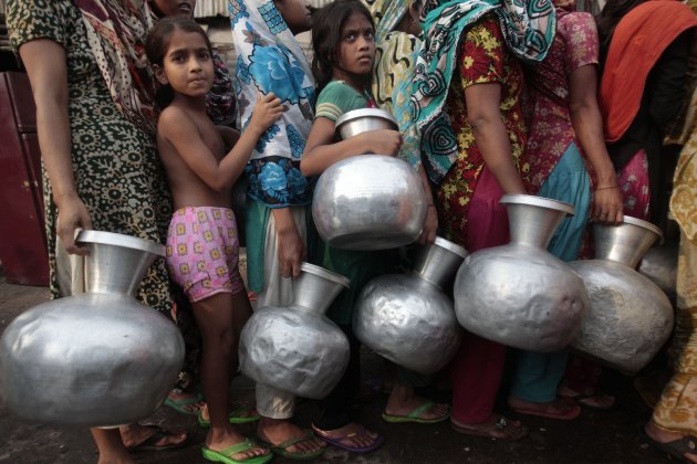 People wait in line with water pots as they collect water from a lorry from WASA in outskirts of Dhaka