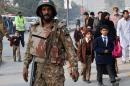 A Pakistani soldier stands guard as parents leave with their children near the site of an attack by Taliban gunmen on a school in Peshawar, on December 16, 2014