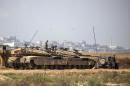 Israeli soldiers sit atop their tanks on the Israeli side of the border with the Gaza Strip, on July 3, 2014