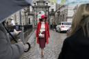 Carmen Negoita a fashion blogger poses for photographs between media umbrellas as rain falls on the first day of London Fashion Week, in London, Friday, Feb. 14, 2014. (AP Photo/Alastair Grant)