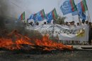 Supporters of Islami Jamiat Talaba, a student wing of Pakistan religious and political party Jamaat-e-Islami, hold their party flags as they burn tyres on the road during an anti-American demonstration in Peshawar