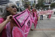 Karen Boyer, of Portland, Ore., displays her sign during a Code Pink protest before the Republican National Convention, Sunday, Aug. 26, 2012, in Tampa, Fla. (AP Photo/Dave Martin)