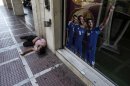 A man begging for alms lays by a sticker with Greece' national football team players one day before general elections in Athens, on Saturday, June 16 2012. Greeks vote for the second time in six weeks Sunday amid fears that the country could be forced out of the euro if they reject the strict austerity measures taken in return for billions of euros in rescue loans from other European countries and the International Monetary Fund. (AP Photo/Kostas Tsironis)