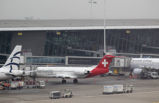 Baggage carts make their way past a Helvetic Airways aircraft from which millions' of dollars worth of diamonds were stolen on the tarmac of Brussels international airport, Tuesday, Feb. 19, 2013. Eight armed and masked men made a hole in a security fence at Brussels' international airport, drove onto the tarmac and snatched millions of dollars' worth of diamonds from the hold of a Swiss-bound plane without firing a shot, authorities said Tuesday. (AP Photo/Yves Logghe)