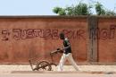 A man wheels a cart past a wall with graffiti reading "Justice for me" in Ouagadougou on October 1, 2015
