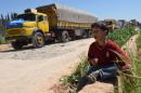 A Syrian child eats as he sits near a convoy of trucks from the World Food Programme and UNICEF carrying international aid, en route to the rebel held area of Al-Rastan north of Homs, on April 21, 2015