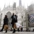 People walk past the Duomo cathedral in downtown Milan