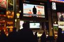 Passers-by look at a TV screen in Tokyo on January 20, 2015, showing news reports about Japanese nationals kidnapped by the Islamic State group