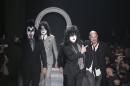 American fashion designer John Varvatos, right, is accompanied by Rock Band Kiss as he acknowledges the applause of the audience, at the end of his men's Autumn-Winter 2014 collection, part of the Milan Fashion Week, unveiled in Milan, Italy, Saturday, Jan. 11, 2014. (AP Photo/Antonio Calanni)