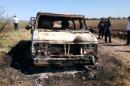 In this Nov. 21, 2015 photo, Mexican authorities inspect a burnt out van suspected to belong to a couple of Australian tourists missing for more than a week, in Sinaloa, Mexico. Two burned bodies where reportedly found inside the vehicle. The toursits, Dean Lucas and Adam Coleman were traveling from Edmonton, Canada and were scheduled to arrive on Nov. 21 in the city of Guadalajara but failed to appear. (AP Photo)