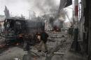 A policeman calls for help as he stands near a burning site after a bomb blast in Quetta