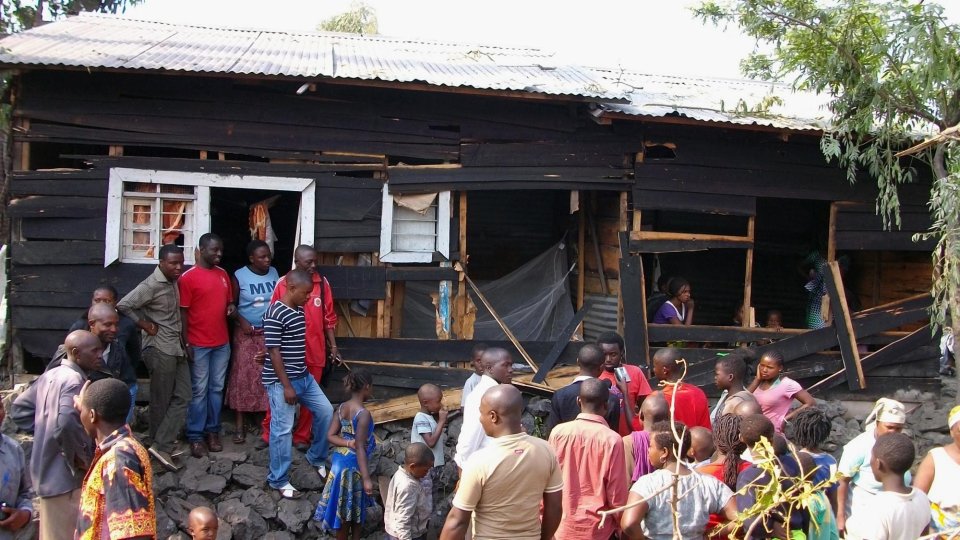 Onlookers gather around a house damaged by overnight shelling in Goma, eastern Congo, Thursday, Aug. 29, 2013. Fighting from the war in eastern Congo that pits U.N. and Congolese forces against rebels spilled over into Rwanda on Thursday when 10 shells landed in a Rwandan border town and a nearby village, killing at least one person, authorities said. (AP Photo/Alain Wandimoyi)
