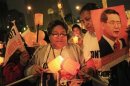 Supporters light candles while holding images of former President Fujimori during a vigil for his recovery outside San Felipe Clinic in Lima