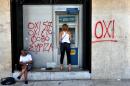A woman withdraws money from an ATM machine next to graffiti reading" No to fear" in Thessaloniki on July 6, 2015