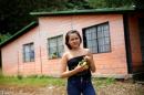 Iznaga holds mangoes and other tropical fruits while posing for a picture next to her house in La Fria