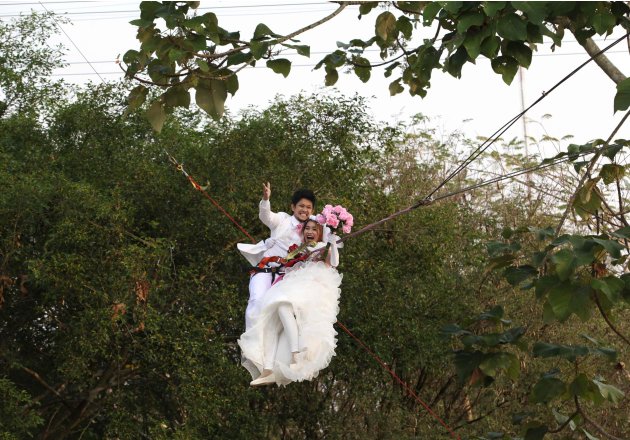 Thai groom Prasit Rangsiyawong and his bride Varuttaon Rangsiyawong fly while attached to cables during a wedding ceremony in Prachin Buri province