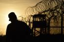 A US soldier walks next to the razor wire-topped fence at the abandoned "Camp X-Ray" detention facility at the US Naval Station in Guantanamo Bay, Cuba, April 2014