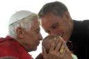 Pope Benedict XVI kisses a child held by private secretary Monsignor Georg Ganswein before conducting mass at Bresso airport near Milan